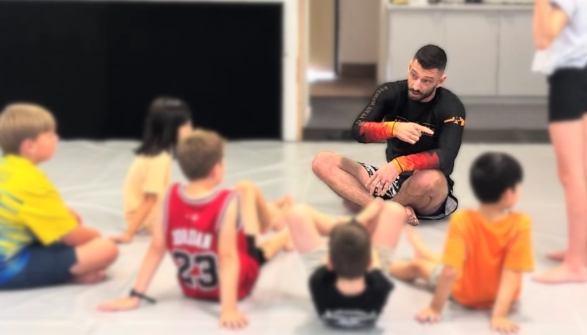 coach Stu sits cross logged and explains a concept to students