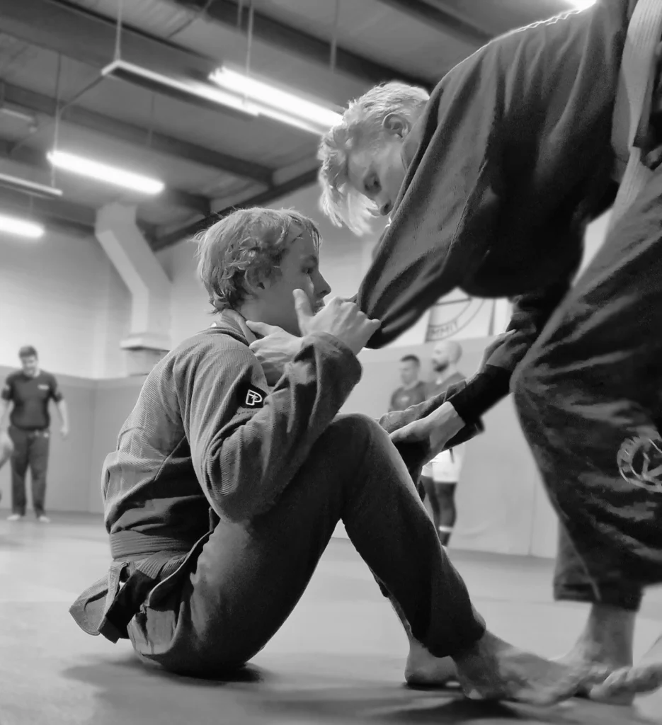a grappler takes a seated guard and assesses his opponents entry